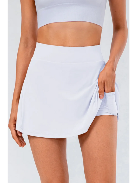 Babe Beachwear white pleated tennis skirt with pockets worn by woman with matching crop top