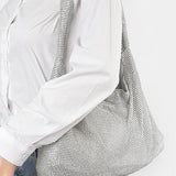 Artini Accessories Quilted Shoulder bag in silver metallic worn on shoulder with white shirt and jeans