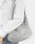 Artini Accessories Quilted Shoulder bag in silver metallic worn on shoulder with white shirt and jeans