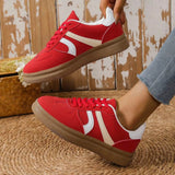 red contrast round toe sneakers with white stripes and brown sole worn with jeans
