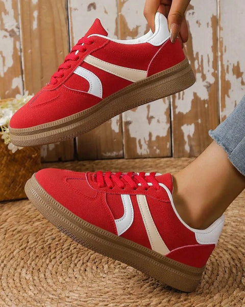 red contrast round toe sneakers with white stripes and brown sole worn with jeans