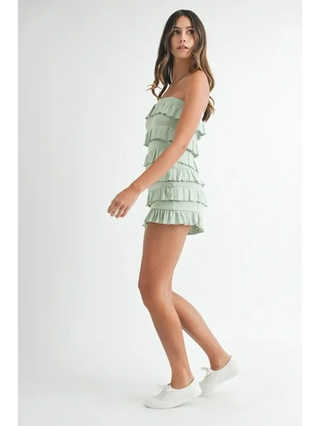 Woman wearing a green ruffled tube romper by Trendsi with white sneakers on a white background