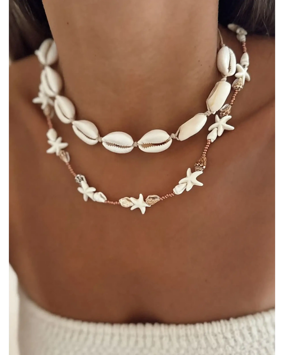 Seashell layered necklace for beach featuring white shell and starfish designs on a model's neck