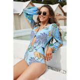 Beach Babes sexty cutout long sleeve swimsuit in blue with tropical leaf print worn by smiling woman