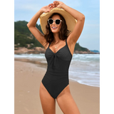 Beach Babes sexy one-piece bathing suit in black with bow detail worn by woman at the beach
