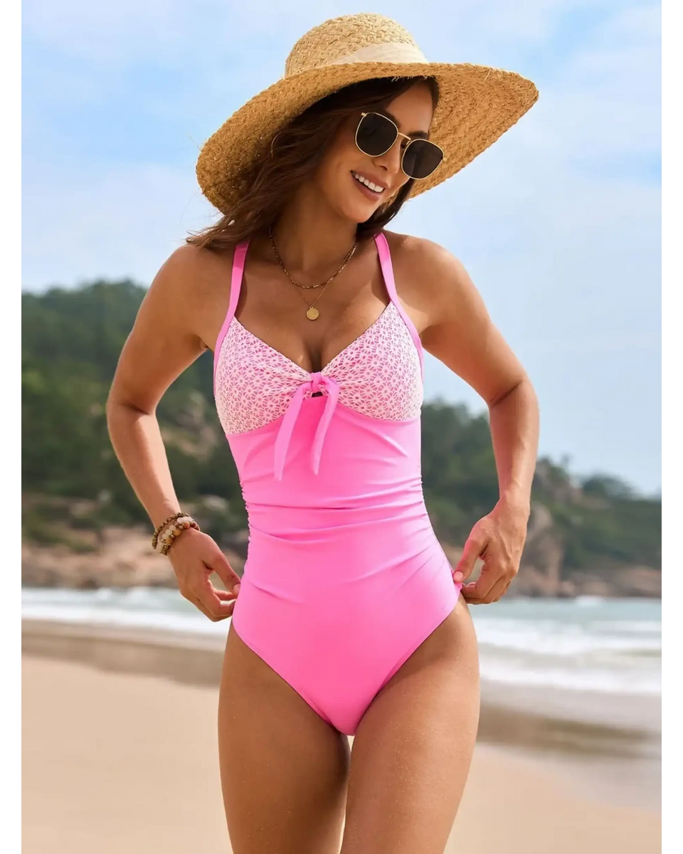 Beach Babes sexy one-piece bathing suit in pink with patterned top worn by woman on the beach