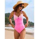 Beach Babes sexy one-piece bathing suit in pink with patterned top worn by woman on the beach