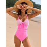 Beach Babes sexy one-piece bathing suit in pink with lace detail worn by woman on the beach