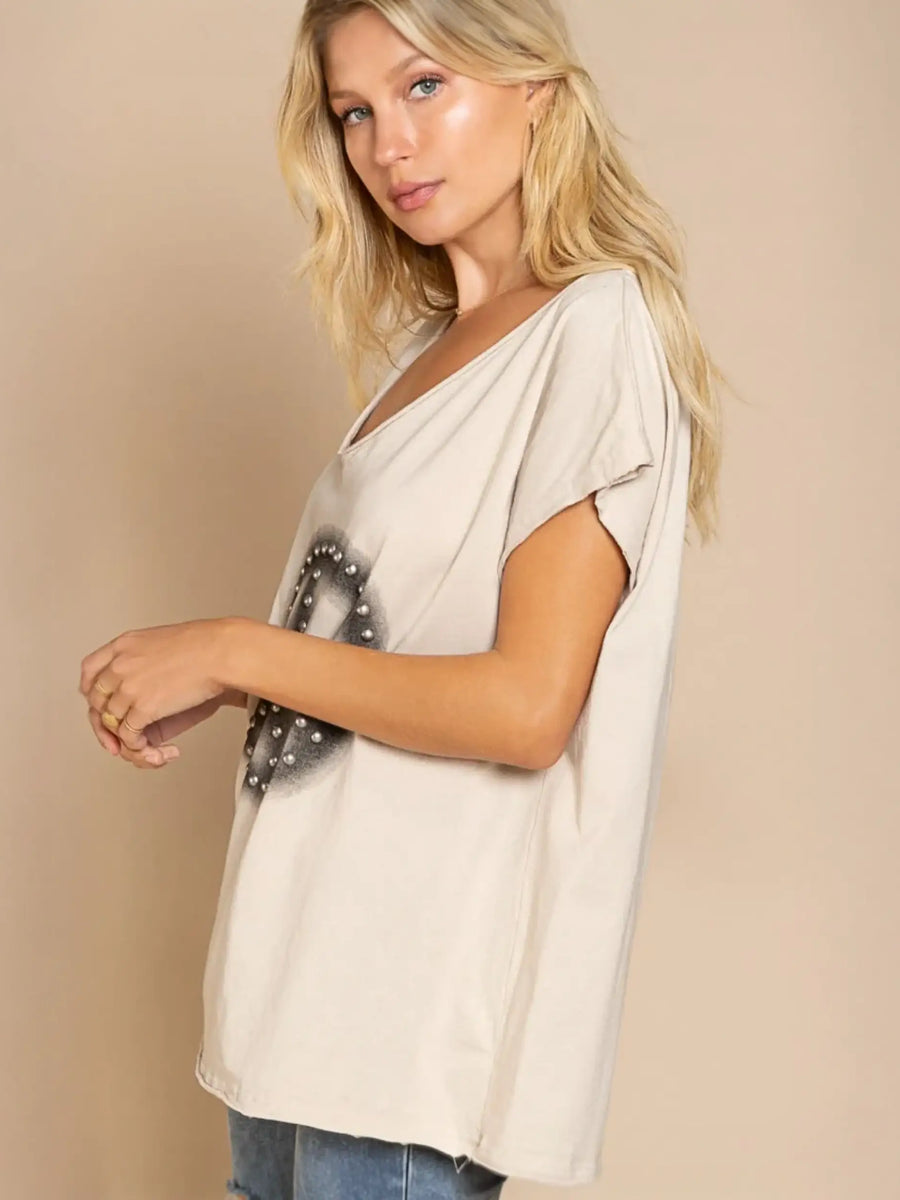 Loose beige V-neck tee with peace sign studded design in fitting room