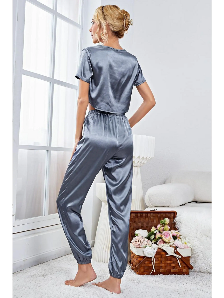 Woman wearing silky lightweight crop top and joggers set in gray satin fabric by Babe Beachwear indoors