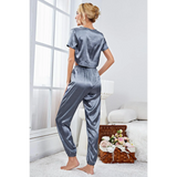 Woman wearing silky lightweight crop top and joggers set in gray satin fabric by Babe Beachwear indoors