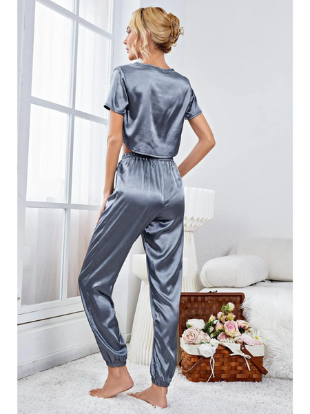 Woman wearing silky lightweight crop top and joggers set in gray satin fabric by Babe Beachwear indoors