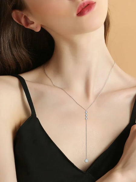 Elegant 1.3 carat drop necklace worn by woman in black dress featuring delicate silver chain and sparkling pendant