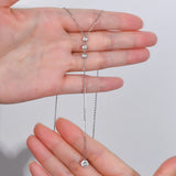 Babe Beachwaer 1.3 carat drop necklace with three small stones and a larger pendant held between hands