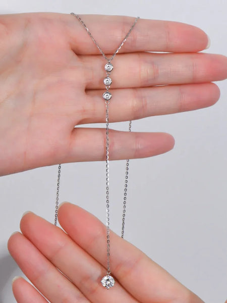 Babe Beachwaer 1.3 carat drop necklace with three small stones and a larger pendant held between hands