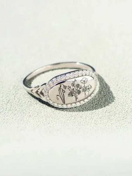  women's summer statement ring with oval floral design and silver band on textured surface