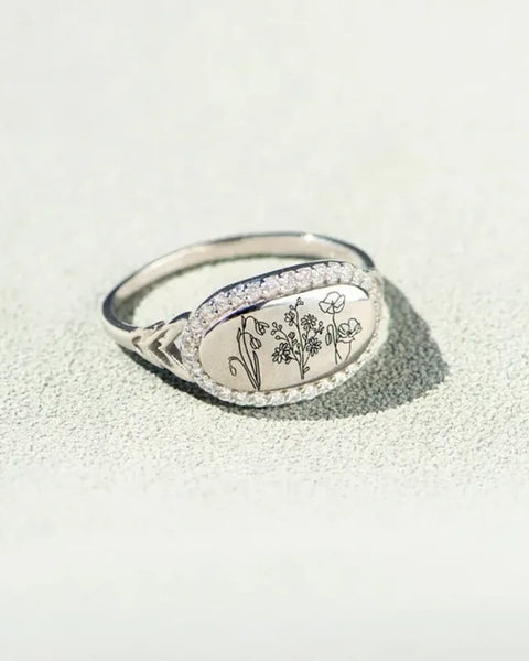  women's summer statement ring with oval floral design and silver band on textured surface