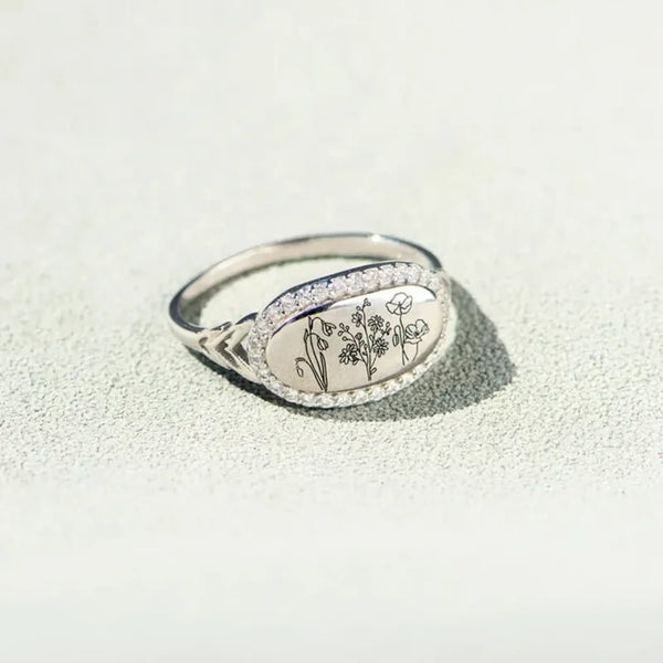  women's summer statement ring with oval floral design and silver band on textured surface