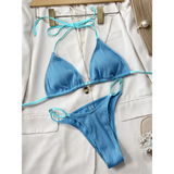 Beach Babes blue ribbed skimpy neon bikini set laid on white blazer with beige accessories