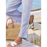 Babe Beachwear striped beach pants for women with button details styled with white sandals at the beach