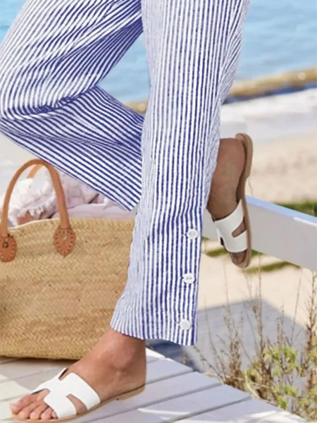 Babe Beachwear striped beach pants for women with button details styled with white sandals at the beach