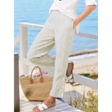 Striped beach pants for women by Babe Beachwear styled with white top and sandals on a wooden deck by the sea