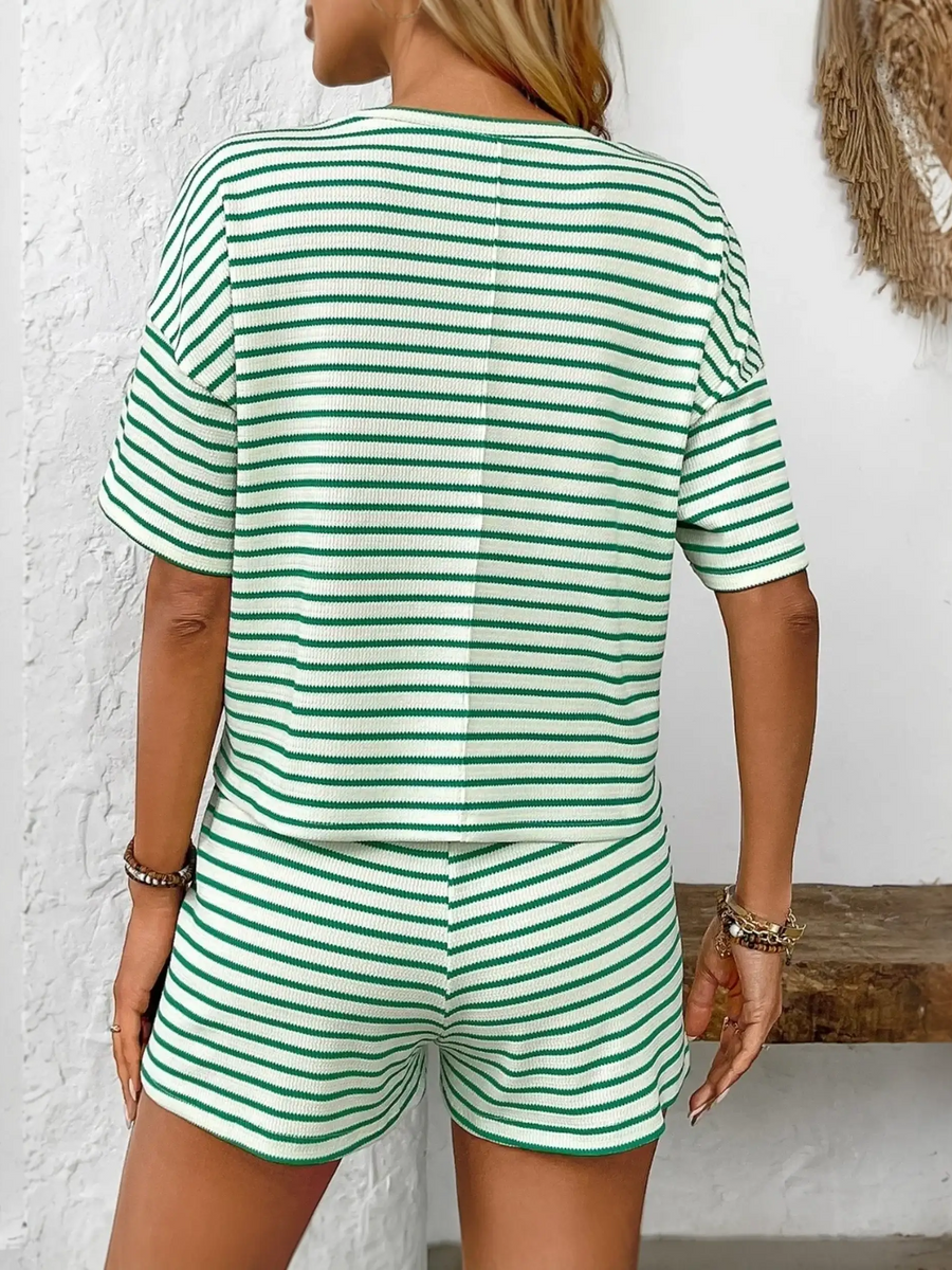 Back view of woman wearing trendy striped summer lounge set with green and white shorts and top