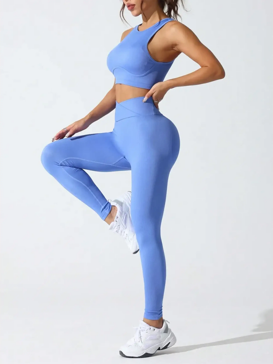 Woman wearing a stylish high waisted gym leggings set in blue by Trendsi posing in athletic shoes
