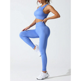 Woman wearing a stylish high waisted gym leggings set in blue by Trendsi posing in athletic shoes