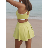 Trendsi Criss Cross Cutout Tennis Skort Dress in light green with white trim shown from back on beach