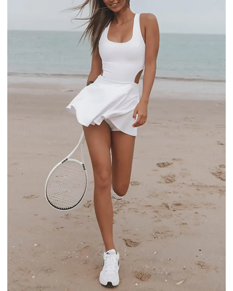 Trendsi Criss Cross Cutout Tennis Skort Dress in white worn on beach holding tennis racket