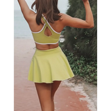 Trendsi Criss Cross Cutout Tennis Skort Dress in light green worn by woman at beachside path
