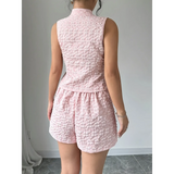 Back view of a woman wearing a pink textured resort vest and short set by Trendsi