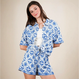 Woman wearing Babe Beachwear tropical blue shorts set featuring a patterned short-sleeve top and matching shorts