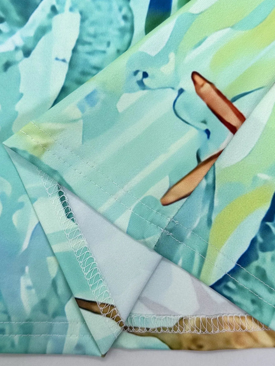 Close-up of turquoise turtle beach dress fabric details by Babe Beachwaer with stitching and vibrant tropical print