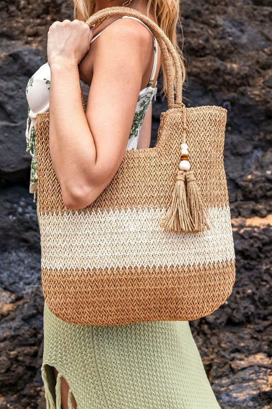 Babe Beachwear two tone straw tote bag with tassel detail carried by woman in green skirt