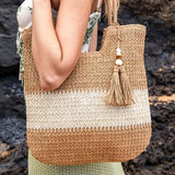 Babe Beachwear two tone straw tote bag with tassel detail carried by woman in green skirt