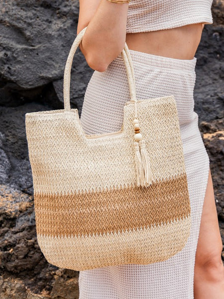 Babe Beachwear two tone straw tote bag with beige and brown stripes carried by woman in white outfit