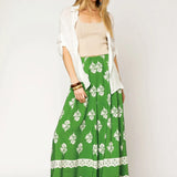 Woman wearing Umgee floral palazzo pants in green with white floral print and a beige top