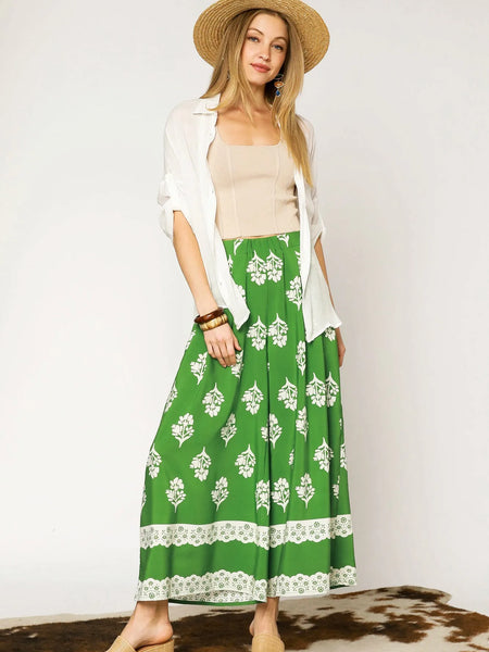 Woman wearing Umgee floral palazzo pants in green with white floral print and a beige top