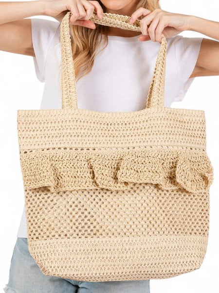 Artini Accessories uniqe ruffle straw bag in natural beige held by a woman wearing white shirt and denim shorts