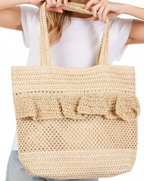 Artini Accessories uniqe ruffle straw bag in natural beige held by a woman wearing white shirt and denim shorts