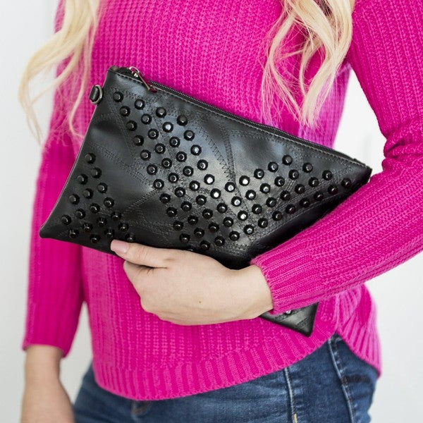 Babe Beachwear black studded leather vacation evening clutch for women held by model in pink sweater