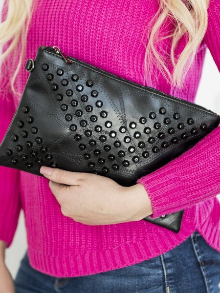 Babe Beachwear black studded leather vacation evening clutch for women held by model in pink sweater