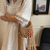 Babe Beachwear vacation-ready boho handbag with woven design and fringe detail worn with white dress