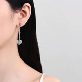 Trendsi 2 carat moissanite heart earrings worn on ear with long silver drop design