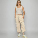 Trendsi beige Cargo Pants with side pockets worn by woman paired with sleeveless top and sneakers