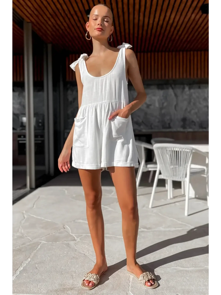 Trendsi casual white vacation romper with shoulder tie straps and front pockets worn outdoors