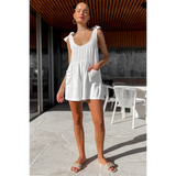 Trendsi casual white vacation romper with shoulder tie straps and front pockets worn outdoors
