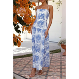 Woman modeling a i white and blue printed empire waist maxi dress worn with tan sandals outdoors